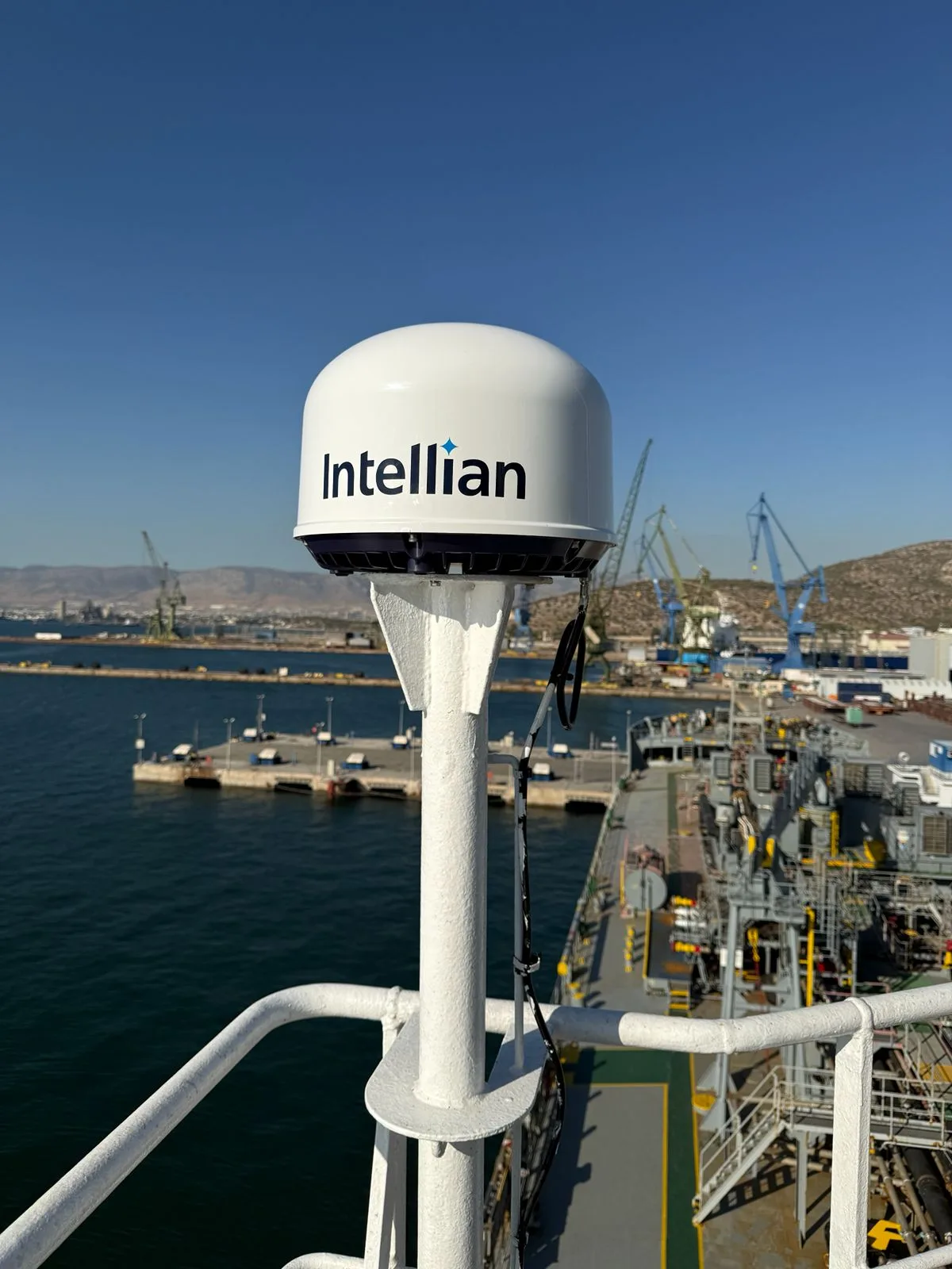 Intellian Iridium antenna installed by Satcenter on a tanker mast above the cargo deck, shipyard cranes behind